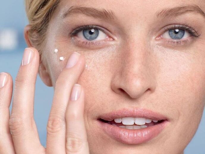 applying cream to rejuvenate the skin around the eyes